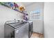 Efficient laundry room with modern washer and dryer units and overhead shelving at 1233 Nelson Park Court, Poinciana, FL 34759