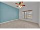 Neutral bedroom featuring plush carpeting, a ceiling fan, and natural light from a window at 13505 Phoenix Dr, Orlando, FL 32828