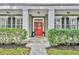 Inviting front porch with a red door, white columns, and meticulously maintained landscaping at 13505 Phoenix Dr, Orlando, FL 32828