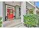 Inviting front porch with a bright red door, sidelights, and manicured landscaping at 13505 Phoenix Dr, Orlando, FL 32828