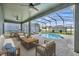 A covered patio area featuring a screened-in pool, ceiling fans, and comfortable seating with a wooden coffee table at 13505 Phoenix Dr, Orlando, FL 32828