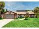 Charming single-story home featuring a brick and vinyl exterior, lush lawn, and an attached garage with a basketball hoop at 140 Margate Mews, Longwood, FL 32779