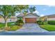 Charming home featuring a two-car garage with a brick-paved driveway, accent lighting, and well-manicured landscaping at 149 Acadia Dr, Kissimmee, FL 34759
