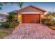 Charming home featuring a two-car garage with a brick-paved driveway, accent lighting, and well-manicured landscaping at 149 Acadia Dr, Kissimmee, FL 34759