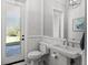 Stylish bathroom with white wainscoting, a pedestal sink, and a door leading to the outdoors at 1590 Harston Ave, Orlando, FL 32814