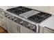 Close up on an updated stainless steel gas stove top with six burners and stainless steel hood at 1590 Harston Ave, Orlando, FL 32814