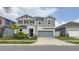 A charming two-story home with a gray exterior, stone accents, and a well-maintained front yard at 1631 Pontiff Pl, Davenport, FL 33896