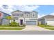 Two-story home with gray siding, stone accents, two car garage, and well-maintained landscaping at 1631 Pontiff Pl, Davenport, FL 33896