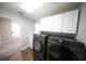 Bright laundry room with a washer and dryer set and overhead storage cabinets at 1631 Pontiff Pl, Davenport, FL 33896