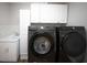 Laundry room featuring a sink, black washer and dryer, and white cabinets at 1631 Pontiff Pl, Davenport, FL 33896
