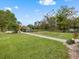 Large backyard area featuring well-maintained green grass, landscaping, and a sidewalk at 2002 Adair St, Ocoee, FL 34761