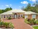 Inviting single-story house with brick driveway, lush landscaping, arched entryway, and a metal roof in a verdant setting at 2002 Adair St, Ocoee, FL 34761
