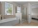 Bathroom showcasing a soaking tub, glass-enclosed shower, neutral tile, and natural light from the window at 2024 Beardsley Dr, Apopka, FL 32703