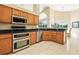 Bright kitchen with stainless steel appliances, tile flooring, granite countertops, and wooden cabinets at 2598 Ekana Dr, Oviedo, FL 32765