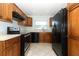 Kitchen features wood cabinets, black appliances, tile flooring, and a bright window for natural light at 2828 Whispering Way, Winter Park, FL 32792