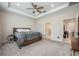 Bright bedroom with carpeted floors, tray ceilings, and adjacent bathroom and closet at 2938 Bushmead Ct, Ocoee, FL 34761