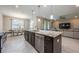 Open concept kitchen with granite counters, island with bar stools, leading into dining & living room at 2938 Bushmead Ct, Ocoee, FL 34761