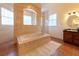 Bright bathroom featuring a jacuzzi tub with tile surround and large window for natural light at 3437 Coronet Ave, Orlando, FL 32833
