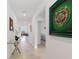 Hallway featuring neutral tile floors, decorative art, and a peek into a sun-filled living room at 423 Pine Tree Blvd, Lake Alfred, FL 33850
