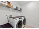 A modern laundry room with white appliances and storage shelves, showcasing clean and organized functionality at 423 Pine Tree Blvd, Lake Alfred, FL 33850