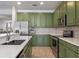 Galley-style kitchen featuring quartz countertops, tile backsplash, stainless steel appliances, and olive-colored cabinetry at 570 Cascading Creek Ln, Winter Garden, FL 34787