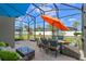 Screened patio with dining and lounge seating under colorful umbrellas overlooking a well-manicured yard at 570 Cascading Creek Ln, Winter Garden, FL 34787