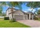 Angle view of a grey home featuring a three-car garage, brick paver driveway, and a palm tree in the front yard at 604 Fosters Grove Loop, Oviedo, FL 32765