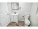 Bathroom with a modern vanity, a mirror, and a toilet, complemented by wood-look flooring at 6354 Hill Rd, Orlando, FL 32810