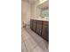 Well-lit bathroom with dual sinks, dark wood cabinets, and gray tiled flooring at 651 Taft Dr, Davenport, FL 33837