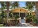 Charming yellow home featuring mature palms, a landscaped front yard, and a welcoming screened-in front porch entrance at 706 Hillcrest St, Orlando, FL 32803