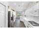 Stylish kitchen featuring white cabinetry, quartz countertops, stainless steel appliances, and unique patterned wallpaper at 842 Bentley Green Cir, Winter Springs, FL 32708