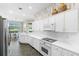 Bright kitchen featuring white cabinets, countertops and backsplash, accented with leaf-patterned wallpaper at 842 Bentley Green Cir, Winter Springs, FL 32708