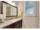 Stylish half bath with dark wood vanity, granite countertop, and decorative mirror at 10742 Belle Maisons Dr, Orlando, FL 32832