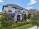 Elegant home with stone-accented entrance, manicured landscaping, and a charming covered porch at 10742 Belle Maisons Dr, Orlando, FL 32832