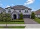 Beautiful two-story home with a stone entrance, lush landscaping, and a two-car garage at 10742 Belle Maisons Dr, Orlando, FL 32832