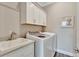 Functional laundry room with white cabinets, a sink, and a modern washer and dryer at 10742 Belle Maisons Dr, Orlando, FL 32832