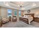Serene main bedroom features a tray ceiling, plush carpeting, and ample natural light from the large windows at 10742 Belle Maisons Dr, Orlando, FL 32832