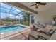 A screened-in lanai with a ceiling fan, comfortable seating, and a pool in the backyard overlooking the lake at 10742 Belle Maisons Dr, Orlando, FL 32832