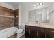 Bathroom with wood look tile shower and tub combo, dark cabinets and quartz counters at 10819 Savona Way, Orlando, FL 32827