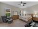 Bright bedroom featuring a large window, wood furniture, a ceiling fan, and neutral carpeting at 10819 Savona Way, Orlando, FL 32827