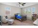 Cozy bedroom with a comfortable chair and a crib, featuring a ceiling fan and natural light at 10819 Savona Way, Orlando, FL 32827