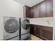 Modern laundry room features front load washer and dryer with white countertop and dark brown cabinets at 10819 Savona Way, Orlando, FL 32827