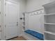 Mudroom with built-in bench, storage hooks, open shelving, and access to the front door at 10819 Savona Way, Orlando, FL 32827