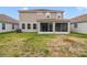 View of the rear exterior with a screened lanai and a spacious lawn at 1115 Oak Bluff Dr, Davenport, FL 33837