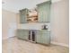 This bar area includes green cabinets, a wine fridge, a beverage cooler and light wood-look ceramic flooring at 1115 Oak Bluff Dr, Davenport, FL 33837