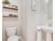 This neutral half-bathroom features a pedestal sink, floating shelves, art and modern toilet at 1115 Oak Bluff Dr, Davenport, FL 33837