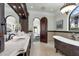 Bathroom with dual sinks, custom cabinetry, a standalone tub, and arched doorways at 1401 Green Cove Rd, Winter Park, FL 32789