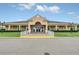 Attractive clubhouse building has an arched entry, white railings, colorful postings, and lush lawn at 1401 Yellow Finch Dr, Davenport, FL 33837