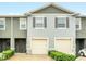 Two-story townhouse with gray facade, two-car garage, and manicured green shrubs at 1401 Yellow Finch Dr, Davenport, FL 33837