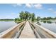 Scenic pond with fountain features wooden bridge leading to an island of mature trees and blue skies at 1401 Yellow Finch Dr, Davenport, FL 33837